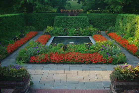 A square fountain surrounded by orange flowers. 